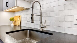 A modern kitchen with a stainless steel sink, a flexible faucet, and a white brick backsplash.