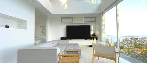 A modern living room with a large sectional sofa, a coffee table, and a TV on a white stand.