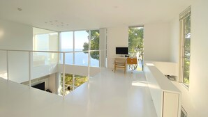 A modern, minimalist room with large windows offering a view of the sea. - Atami Hamada House (Atami)