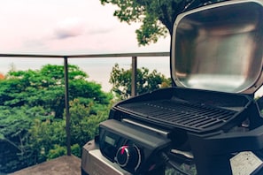 A portable grill with a digital display, set outdoors with a view of trees and a body of water in the background. - Atami Hamada House (Atami)