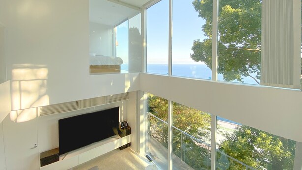 A modern living room with a large flat-screen TV, a sofa, and a dining area. - Atami Hamada House (Atami)