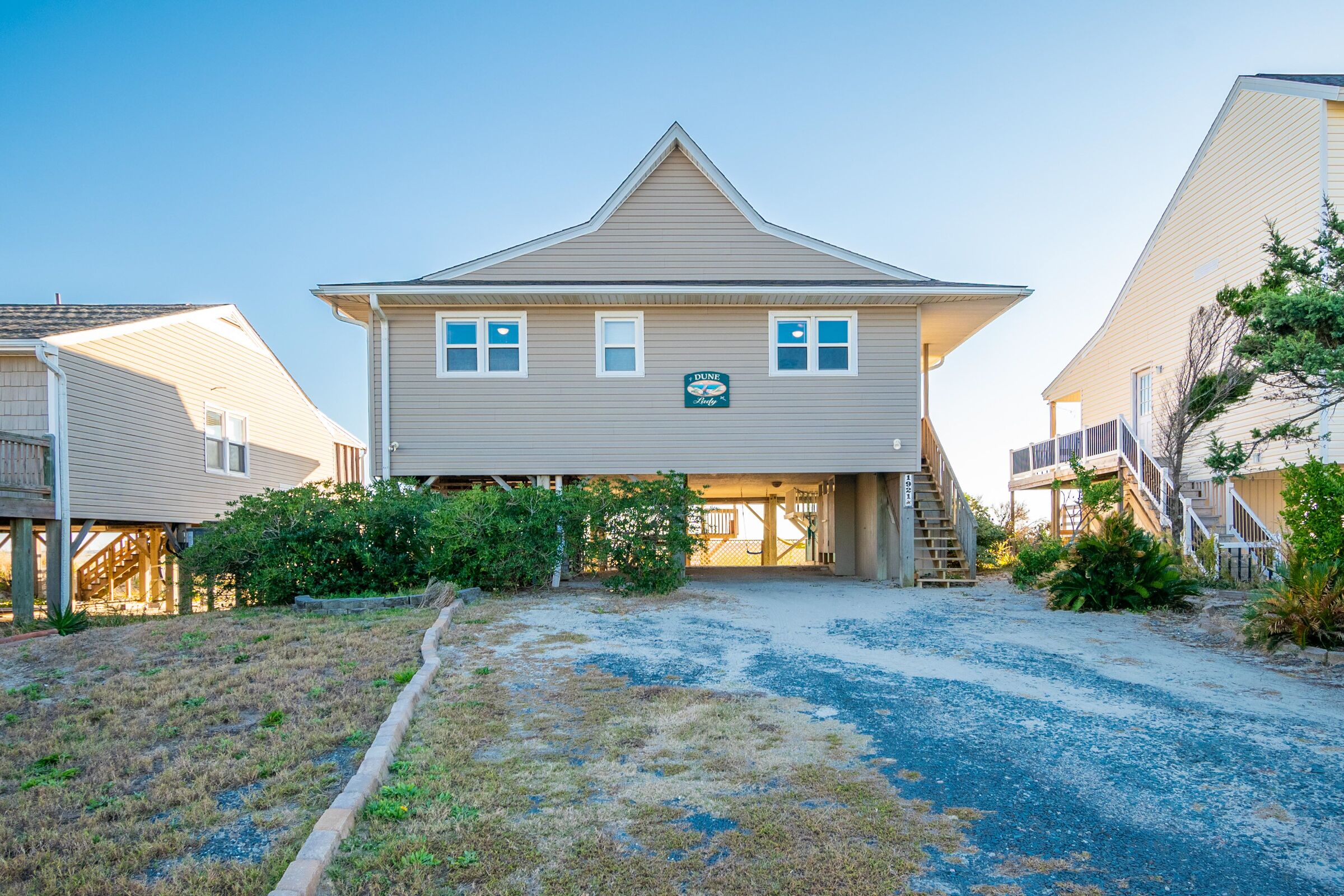 A two-story building with a garage entrance, surrounded by a gravel driveway and small bushes.