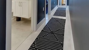 Ein moderner Flur mit einem schwarz-weißen Teppich, weißen Schränken und einem gerahmten Bild an der Wand.