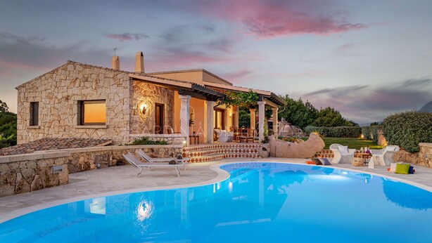 Une maison en pierre avec une piscine, du mobilier d’extérieur et un jardin.