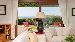 Un salon avec un canapé, une lampe et une vue sur la mer.