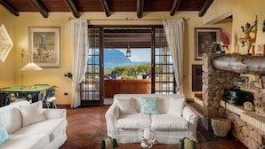 A cozy living room with a white sofa, a dining table, and a view of the ocean.