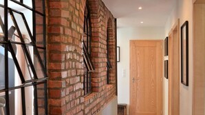 A hallway with a brick wall, a wooden door, and a framed picture on the wall. - L'Atelier de notre Grand-Père - Jacuzzi (Algolsheim)