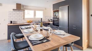 A modern kitchen with a dining area set for six. - L'Atelier de notre Grand-Père - Jacuzzi (Algolsheim)