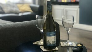 Une bouteille de vin posée sur un dessous de verre, avec deux verres à vin vides à côté.