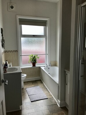 Une salle de bain équipée de toilettes, d’un lavabo, d’une baignoire et d’une fenêtre donnant sur un beau paysage.