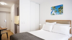 A hotel room with a bed, a desk, and a painting of palm trees. - Séjours & Affaires Paris Bagnolet (Bagnolet)