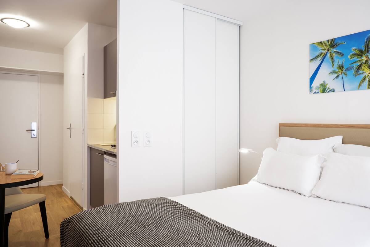 Una habitación de hotel con una cama, un escritorio y un cuadro de palmeras.