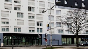 A modern building with a white facade and a black section on the right. There are multiple windows on each floor, and a streetlight is visible in the foreground. - Séjours & Affaires Paris Bagnolet (Bagnolet)