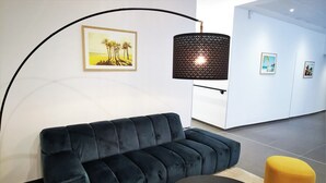 A modern lounge area with a dark blue sofa, two yellow ottomans, and a black coffee table. - Séjours & Affaires Paris Bagnolet (Bagnolet)