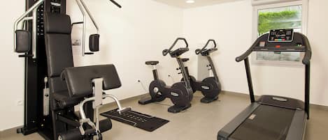 A gym with a treadmill, stationary bikes, and weight machines.