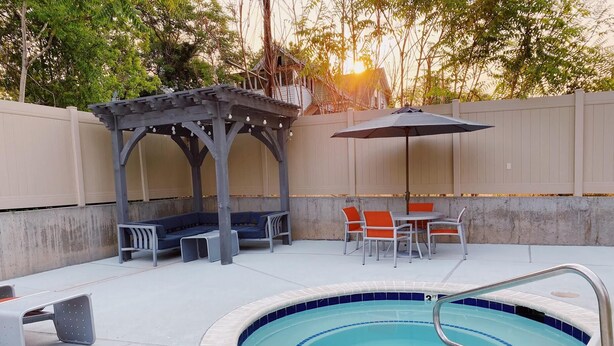 A swimming pool with a covered seating area and a table with chairs.