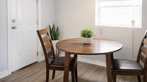 A dining area with a round wooden table, two chairs, and a potted plant on the table. - Downtown Gem • King Bed • Fast WIFI (Salt Lake City)