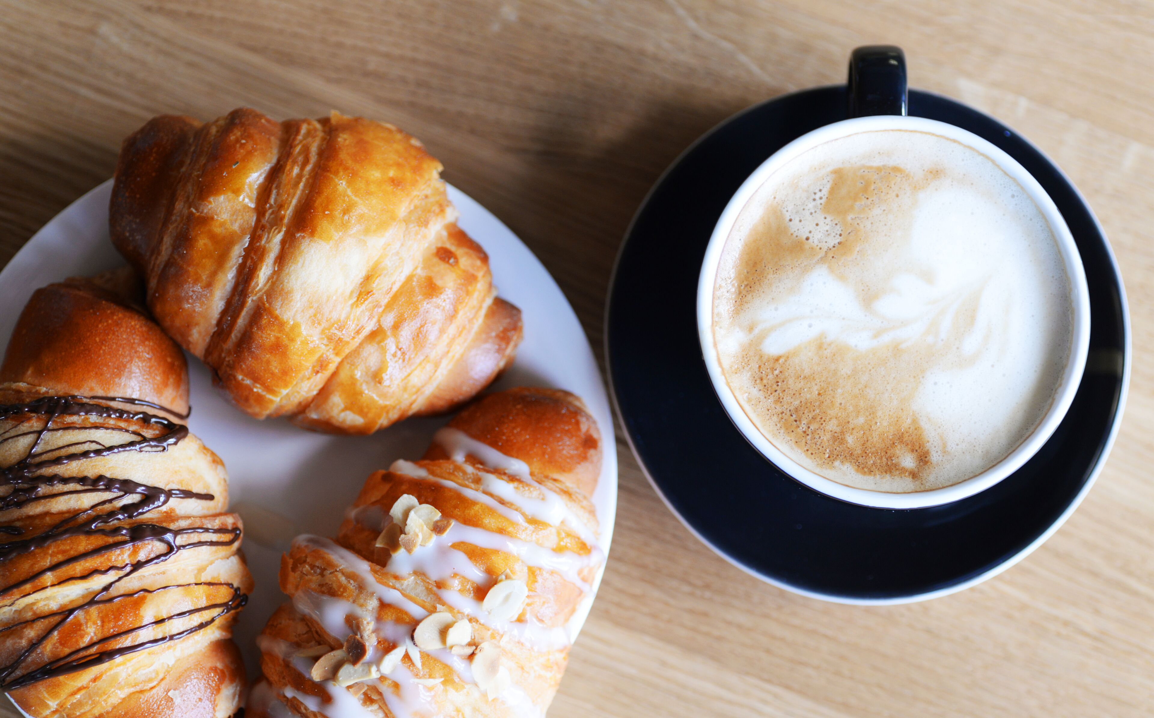 A plate of pastries and a cup of coffee on a wooden table.