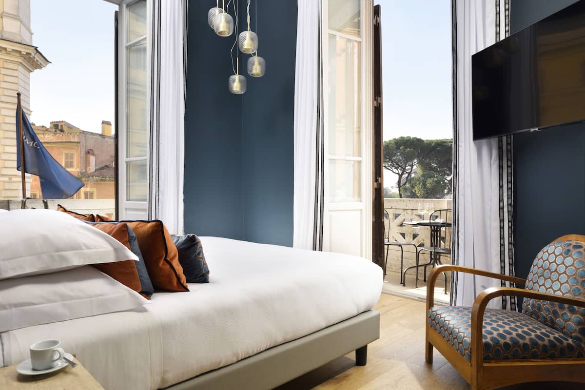 A modern hotel room with a large bed, a wooden chair, and a TV.