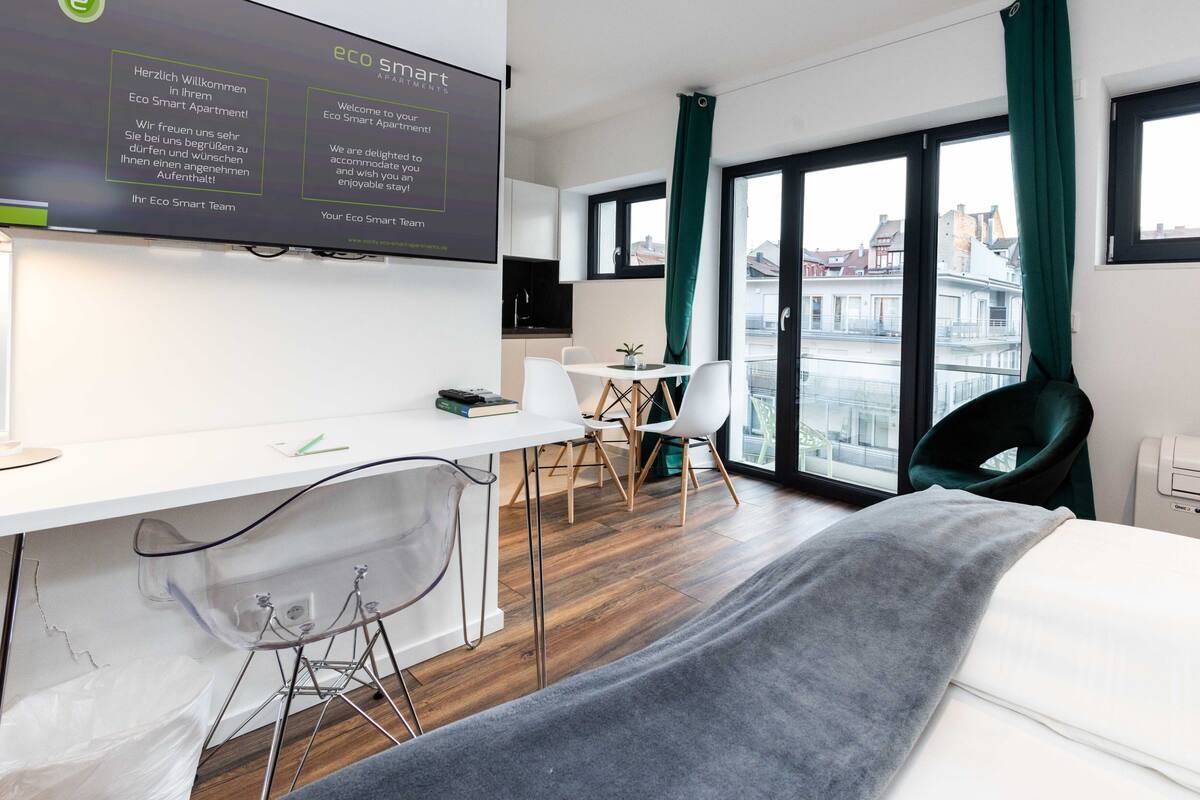 Ein modernes Hotelzimmer mit großem Fenster, Schreibtisch, Stuhl und Bett.