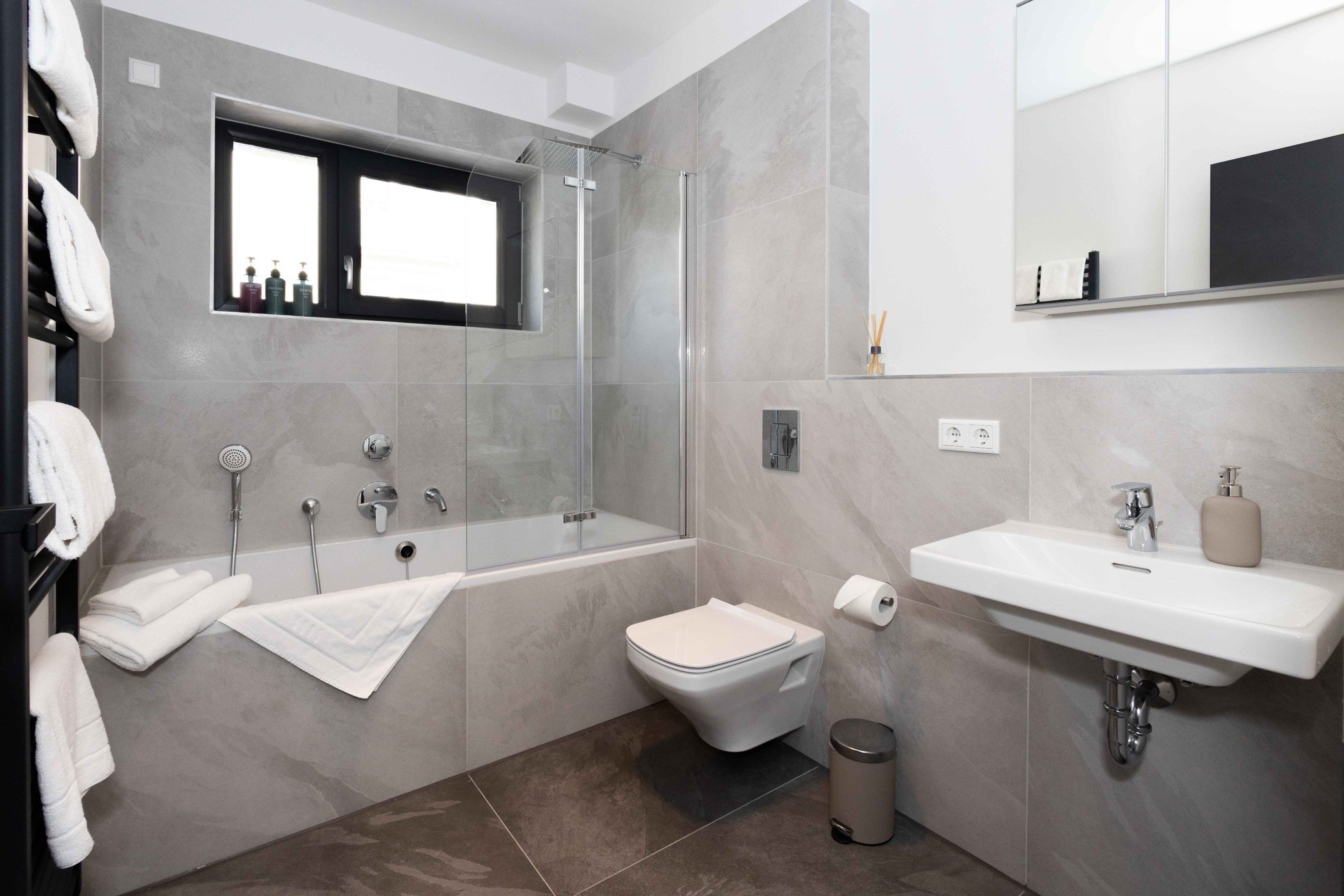 Un baño moderno con ducha de vidrio, una bañera, un inodoro y un lavabo.