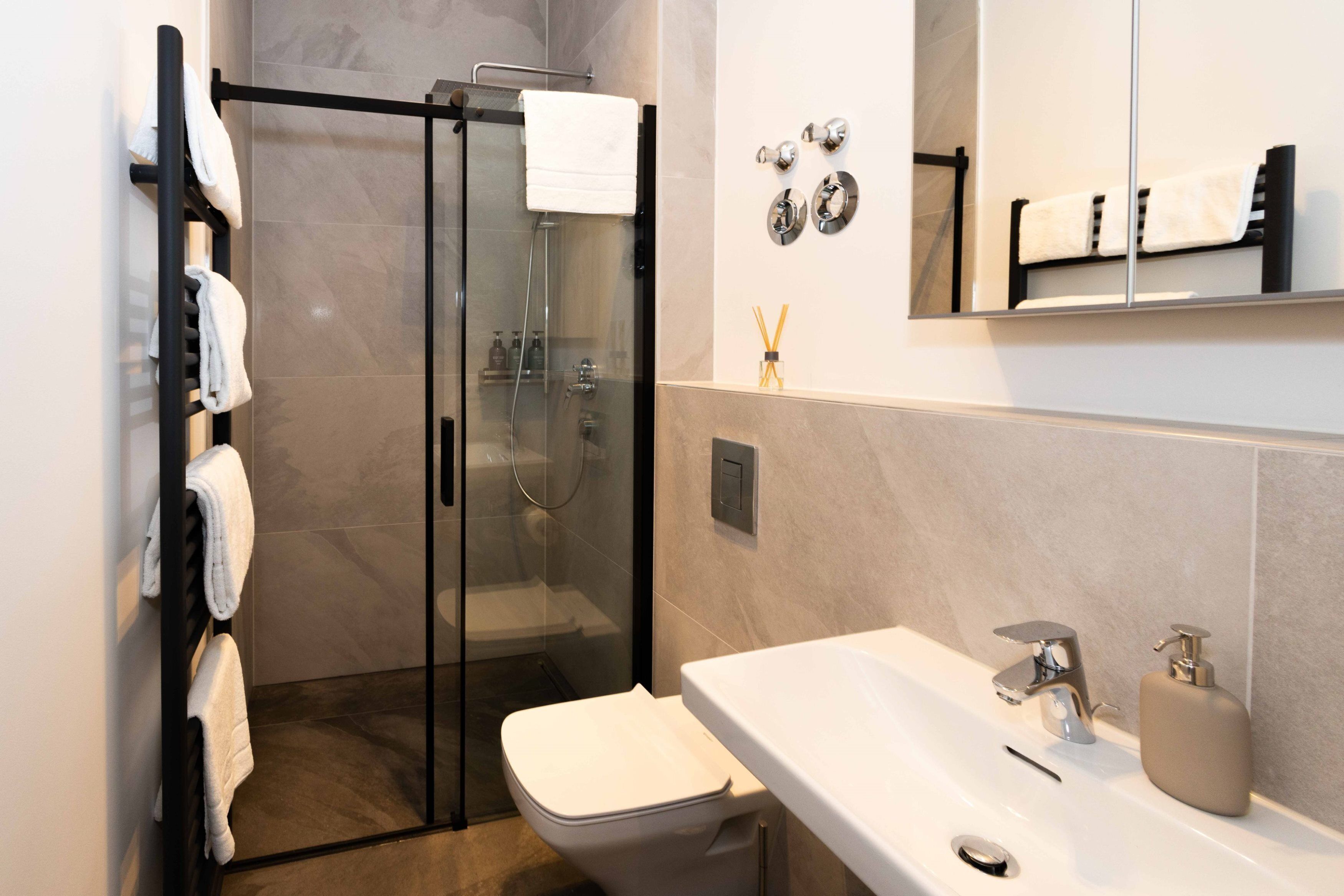 A modern bathroom with a glass-enclosed shower, a white sink, and a mirror above the sink.