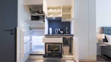 Una cucina compatta con elettrodomestici integrati, tra cui frigorifero, forno e macchina da caffè.