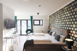Une chambre d’hôtel moderne équipée d  ’un lit, d’un bureau et d’une télévision.