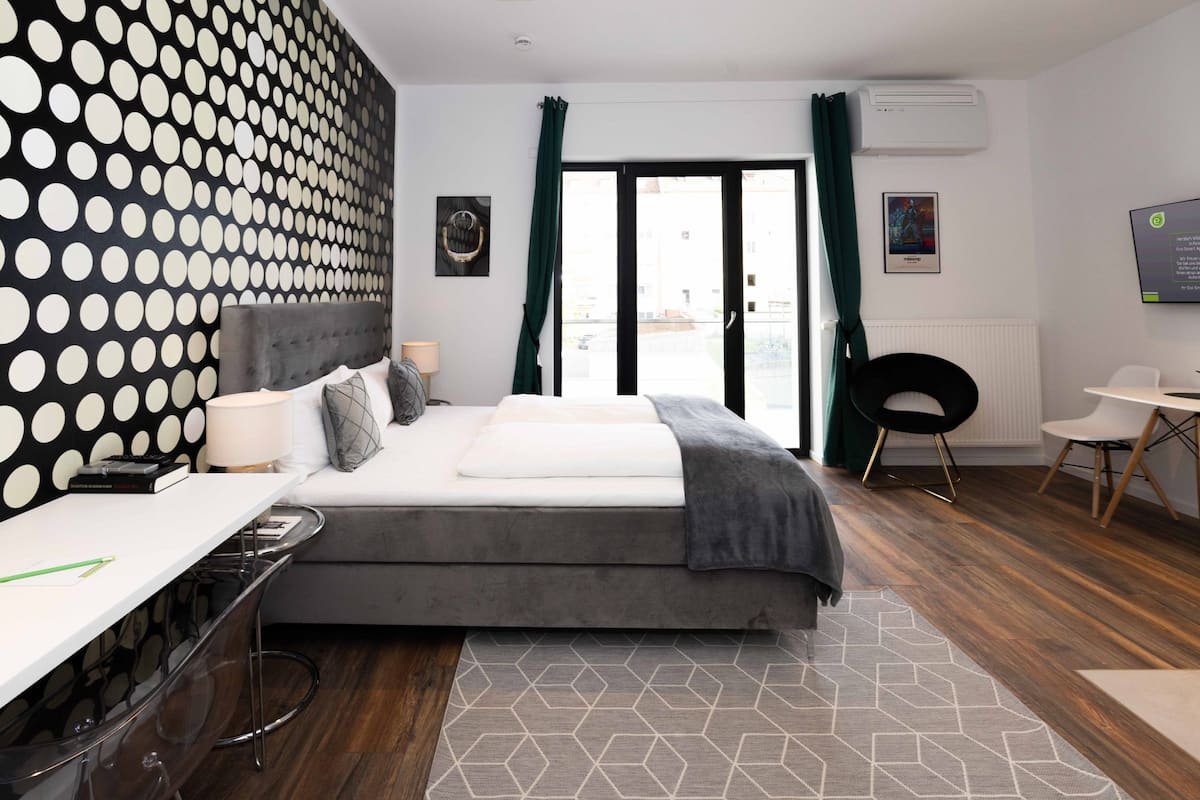 Ein modernes Hotelzimmer mit Bett, Schreibtisch, Stuhl und Blick ins Freie.