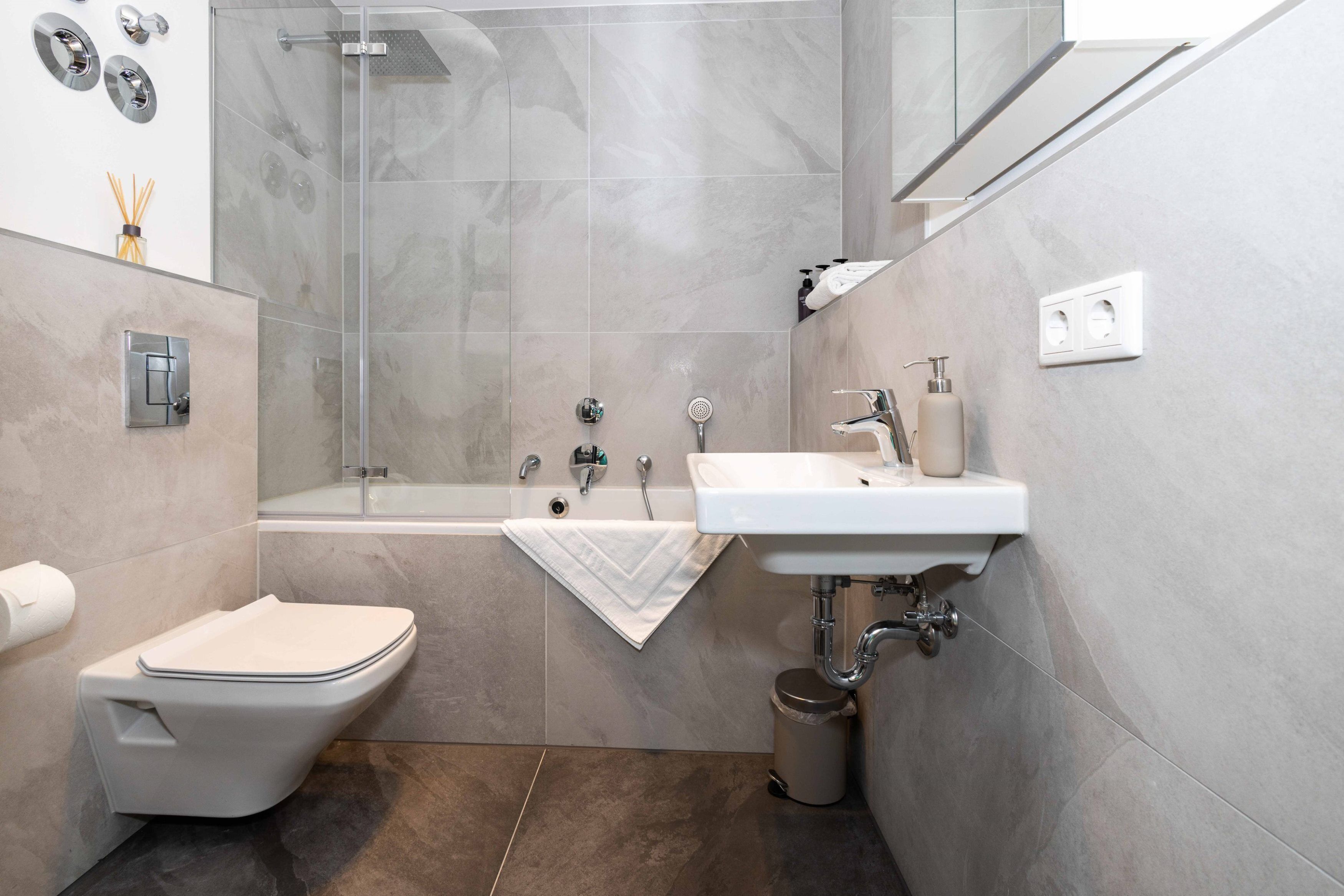 A modern bathroom with a toilet, sink, and shower.