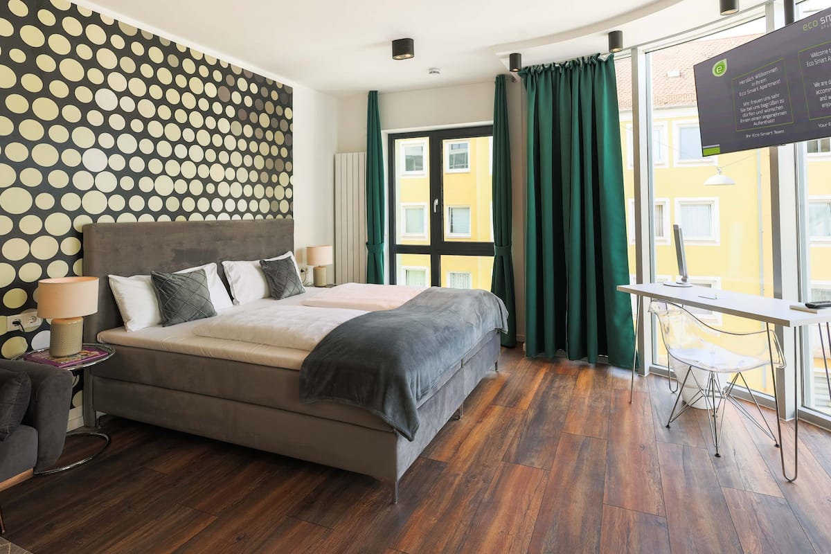 Ein modernes Hotelzimmer mit einem großen Bett, einem Schreibtisch und Blick auf die Stadt.
