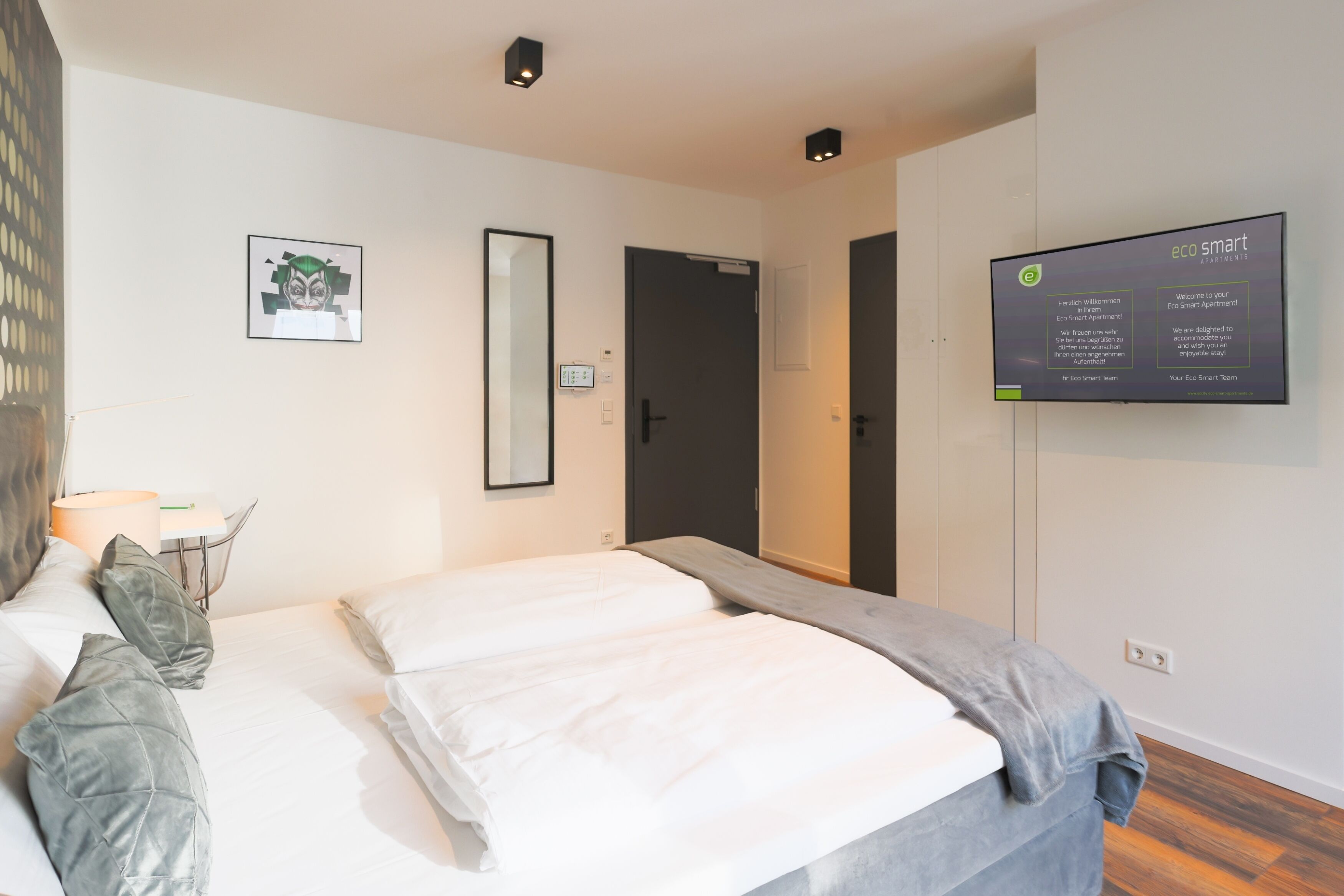 Une chambre d’hôtel moderne équipée d’un lit, d’un bureau et d’un écran de télévision affichant des informations.