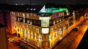 Un hôtel à plusieurs étages, doté d’une structure imposante en angle, de grandes fenêtres et d’un espace de stationnement bien visible.