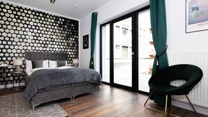 Une chambre moderne avec un lit gris, un mur à motifs et une vue à travers une porte coulissante.