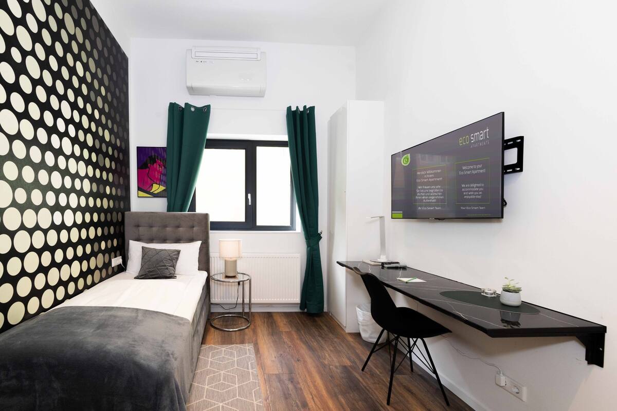 Ein modernes Hotelzimmer mit Bett, Schreibtisch und einem großen Fenster mit Vorhängen.