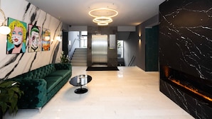 Un hall d’entrée moderne avec un canapé vert, un sol en marbre et un escalier menant à un ascenseur.