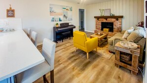 A modern living room with a fireplace, a dining area, and a kitchen visible in the background. - Brandon Peaceful Home w/newly renovated kitchen (Brandon)