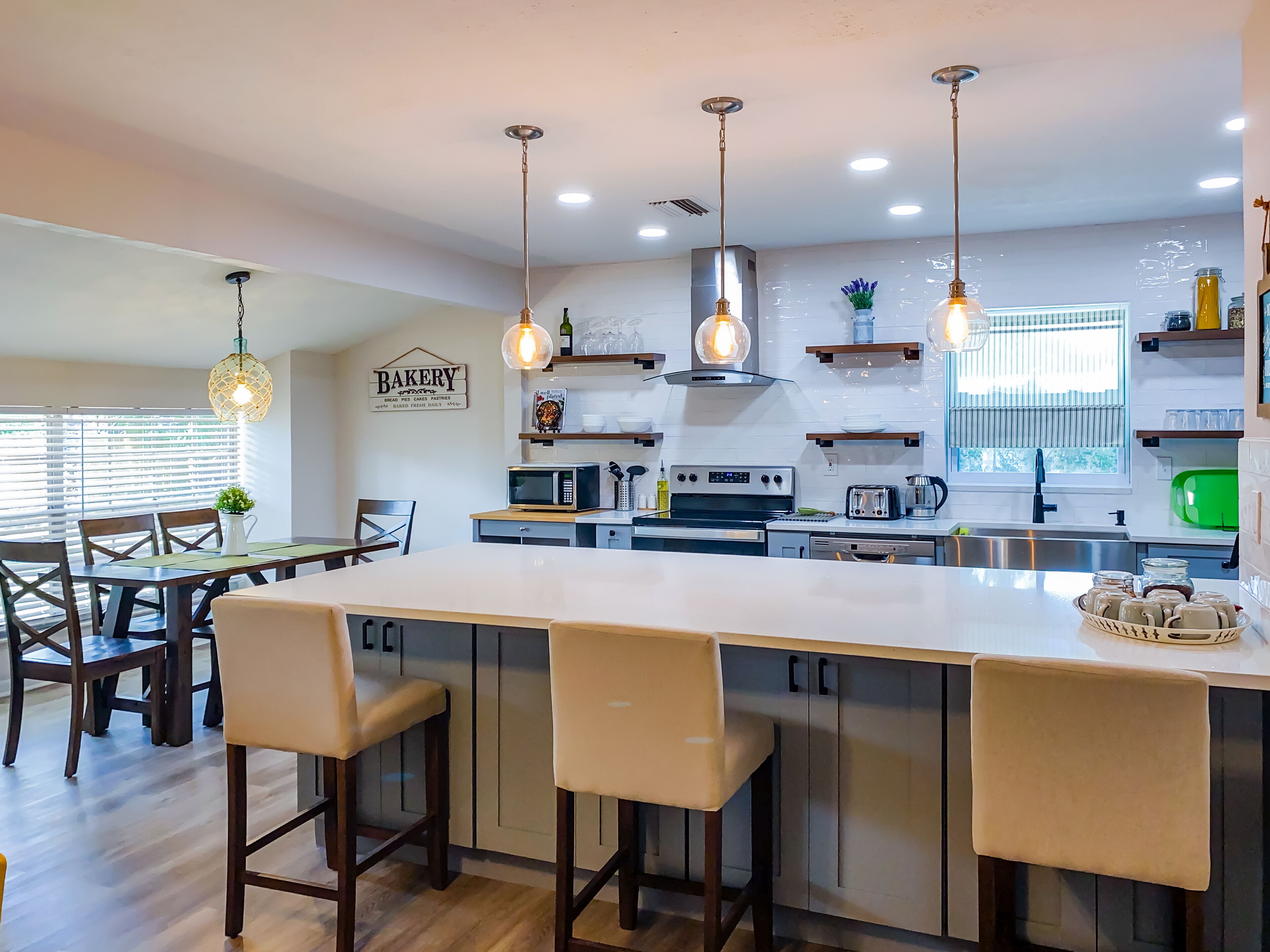 A modern kitchen with a large island, bar stools, and pendant lighting.
