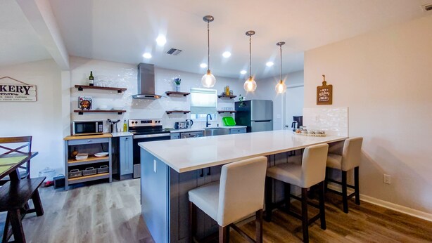 A modern kitchen with a central island, pendant lights, and a dining area with chairs. - Brandon Peaceful Home w/newly renovated kitchen (Brandon)