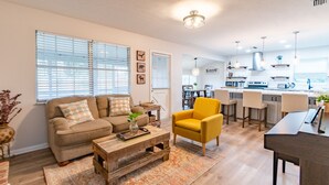 A modern living room with a sofa, armchair, coffee table, and a dining area with chairs and a table. - Brandon Peaceful Home w/newly renovated kitchen (Brandon)