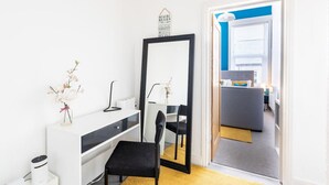 A modern bedroom with a large mirror, a desk, a chair, and a small bedside table. - Judah Suite by Koya Homes (Barry)