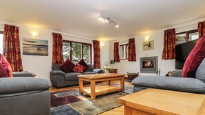 Ein gemütliches Wohnzimmer mit grauen Sofas, einem Holztisch und einem Kamin.