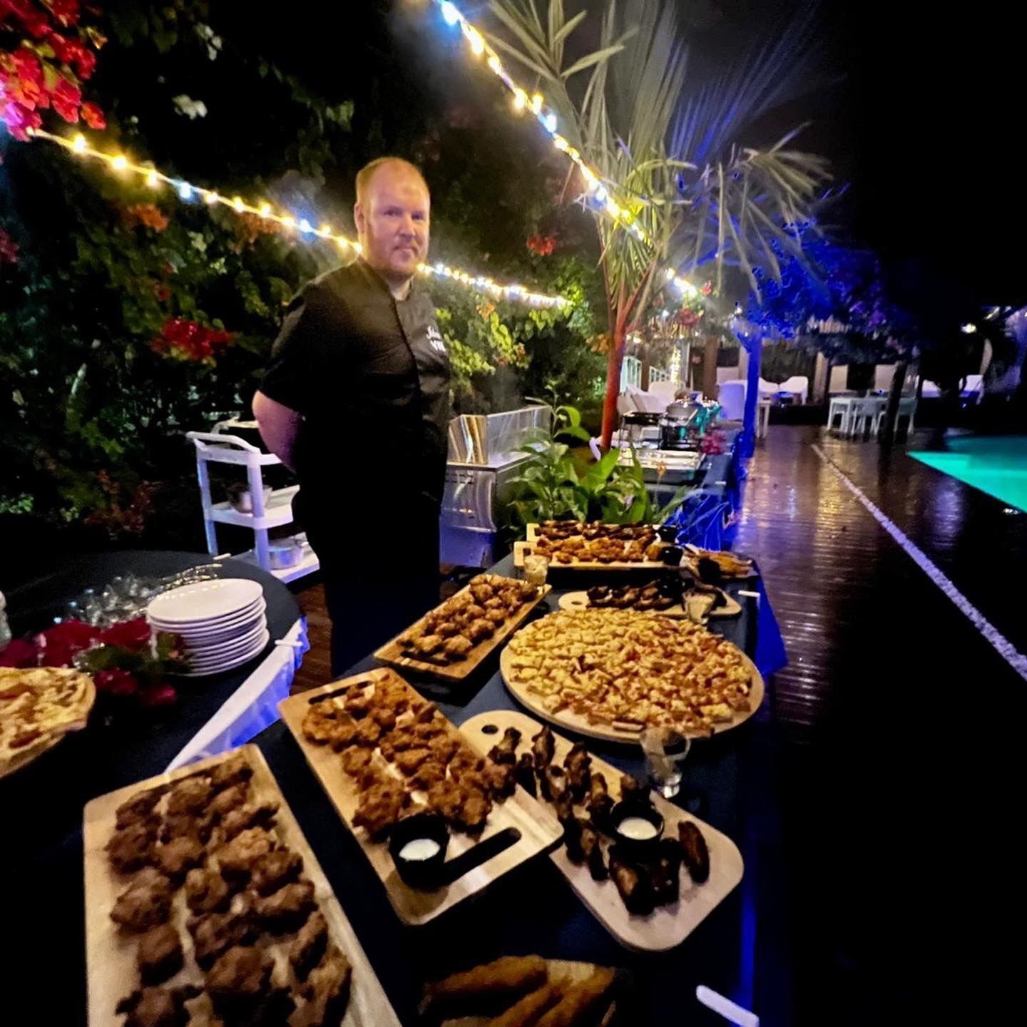 A buffet table with various food items and a person standing behind it.