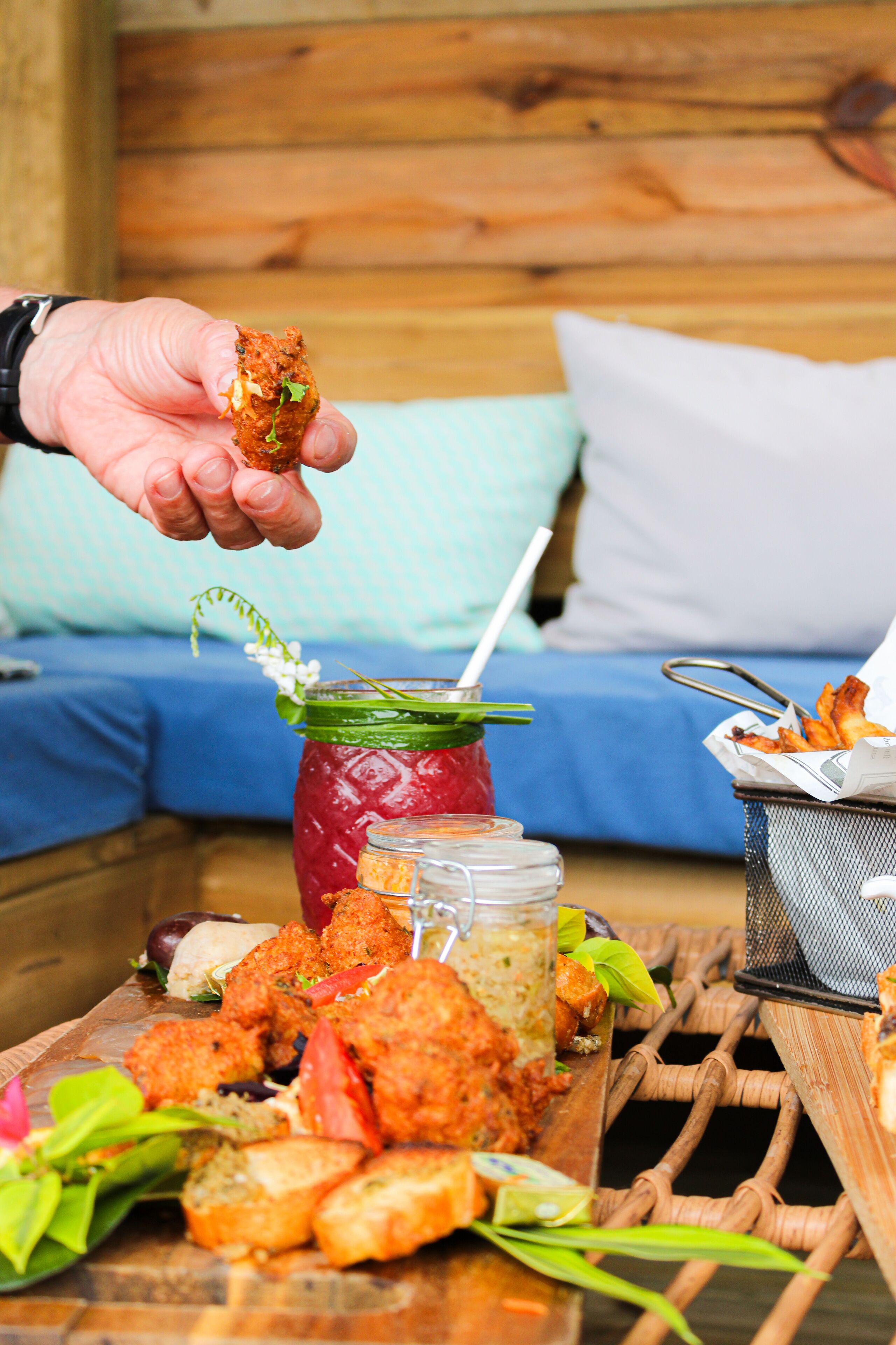 A wooden table with a variety of food items, including bread, vegetables, and a drink in a jar.
