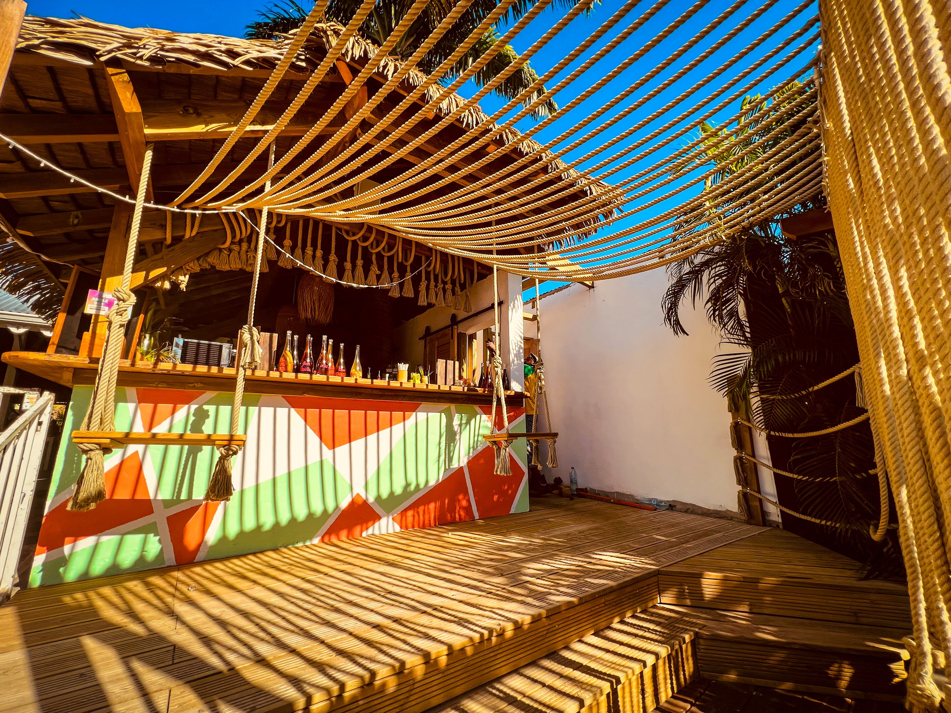 A beachside bar with a wooden deck and a colorful wall.