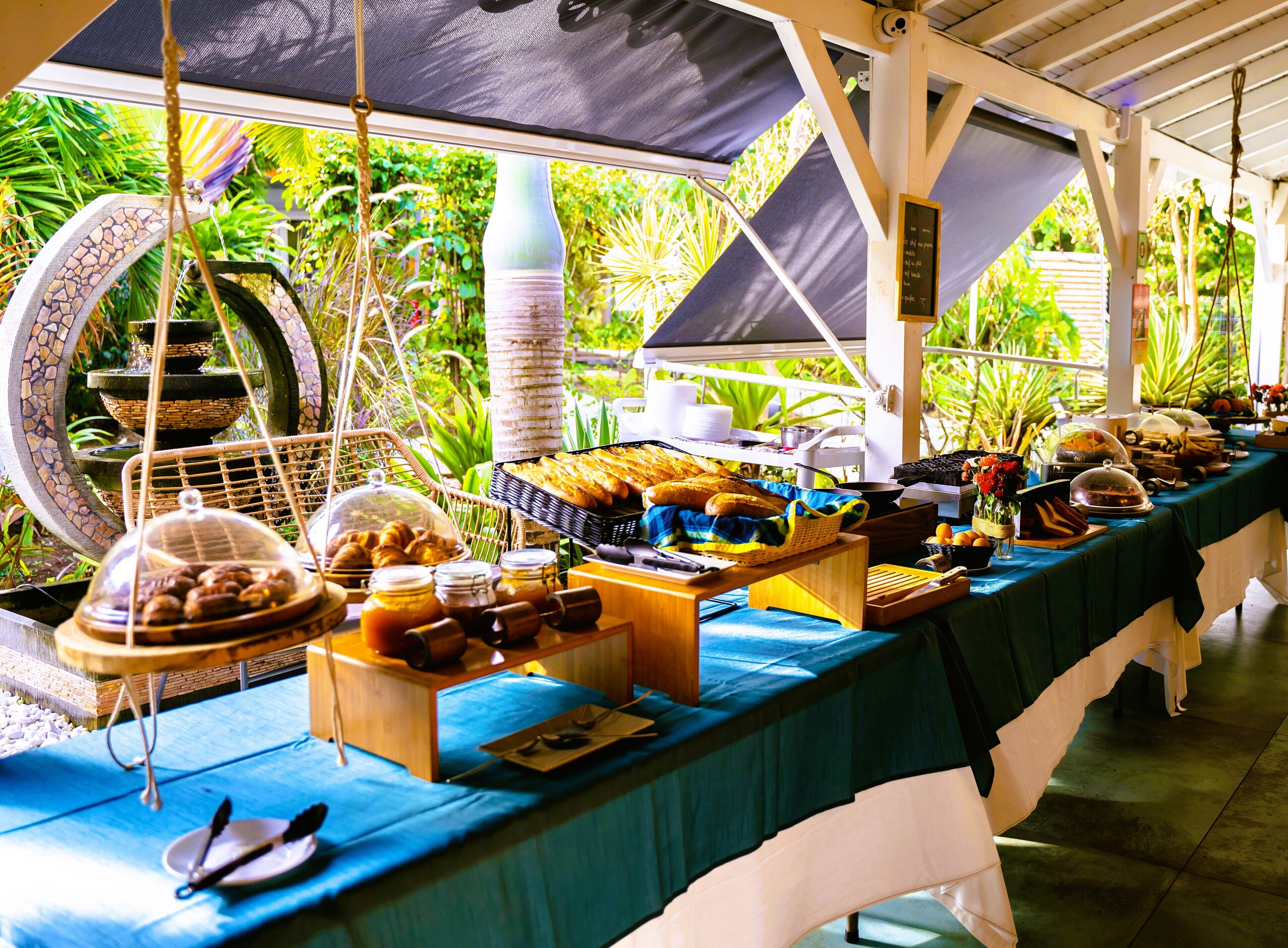 A buffet setup with various food items and a decorative fountain in the background.