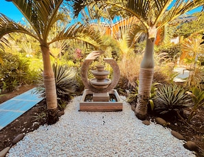Stroll through a tranquil garden oasis surrounded by lush tropical plants and a serene water feature.