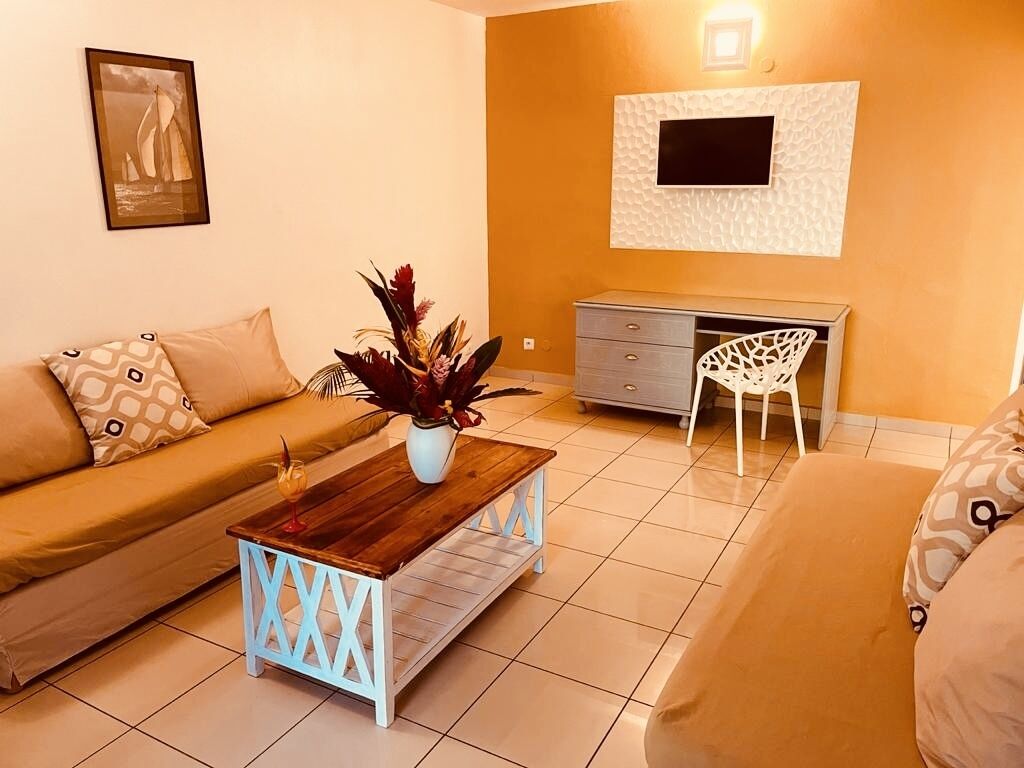 A living room with a sofa, a coffee table, a desk, and a chair.