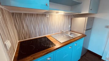 A compact kitchen with a wooden countertop, a sink, and blue cabinets.