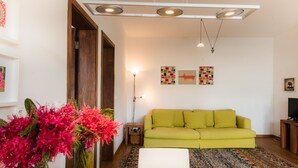 A living room with a green sofa, a wooden coffee table, and a vase of pink flowers.